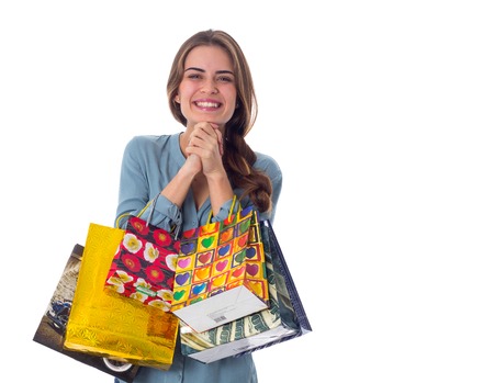 Young pleasant woman in blue blouse holding shopping bags in her hands on white background in studioの写真素材