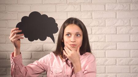 Pretty girl in pink blouse holding a banner with black cloud on the background of white brick  wall