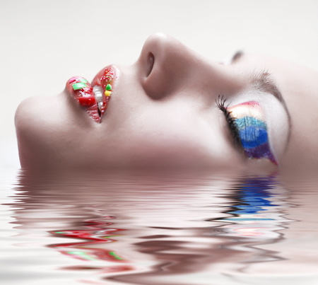 Face of beautiful girl with make-up as a rainbow on eyes and lipsの写真素材