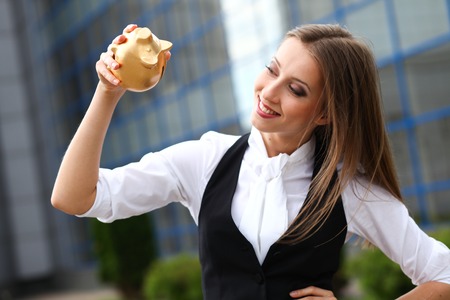 Businesswoman with gold pig monebox near office centreの写真素材