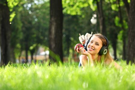 Woman with headphones listening music on the grassの写真素材
