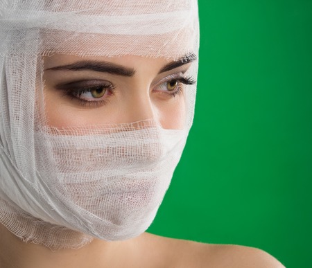 The woman with beautiful brown eyes and a white bandage on her head is against the background of chromakey.の写真素材