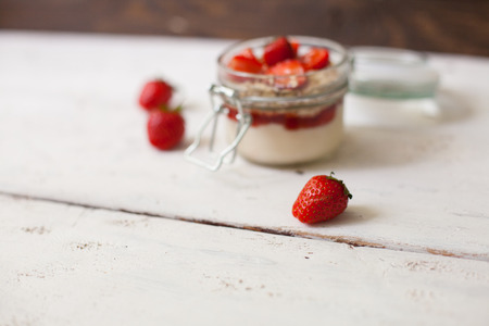 Full glass bowl of yogurt with fresh strawberries on the old white tableの写真素材