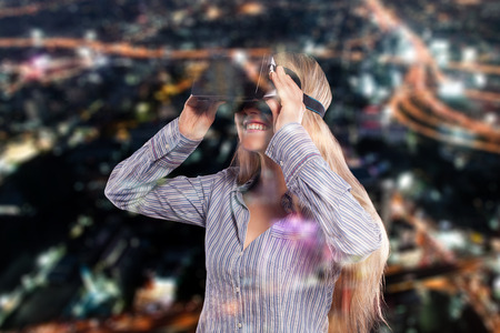 Intrigued woman in grey shirt wearing virtual reality 3D headset and exploring the play on black...