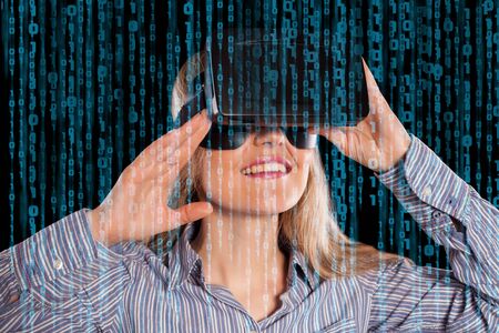 Intrigued woman in grey shirt wearing virtual reality 3D headset and exploring the play on black...