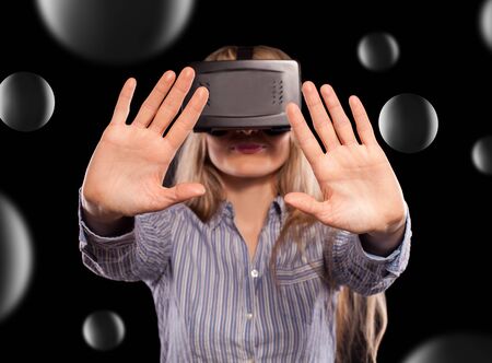 Young woman immersed in interactive virtual reality video game doing gestures on black background.
