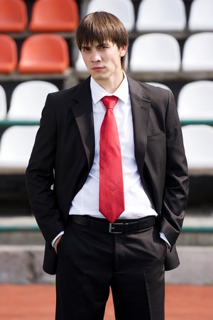 young man in black suit standing near the audience bleachersの写真素材