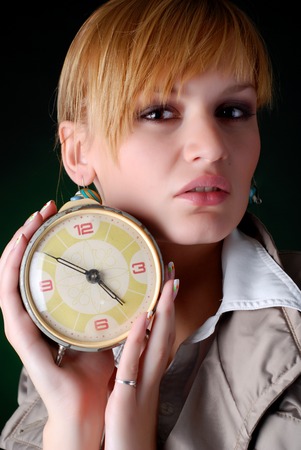 beautiful woman with alarm clock on a black backgroundの写真素材
