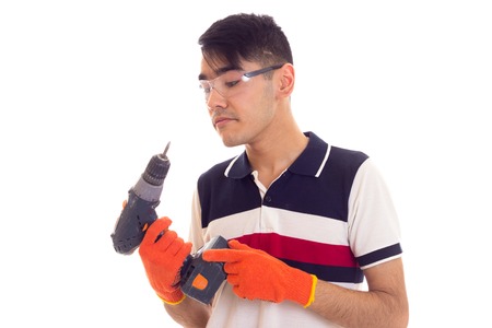 Young man with gloves and glasses holding electric screwdriverの写真素材