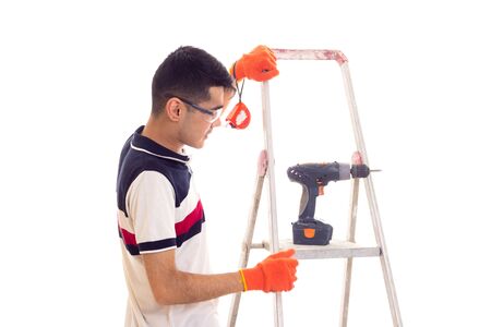Young man with electric screwdriver and ledderの写真素材