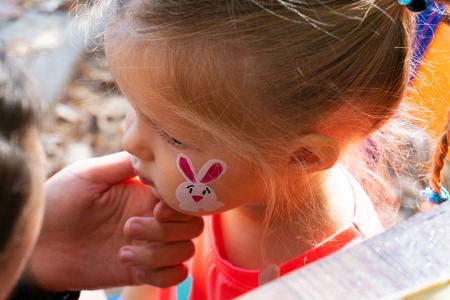 Woman painting on face of girl outdoor
