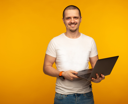 Freelancer man in white shirt holding laptop and smiling