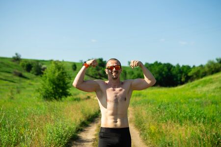 Athletic man in sunglasses without t-shirt show bicepsの写真素材