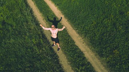 Man athlete runner with hands up standing on roadの写真素材