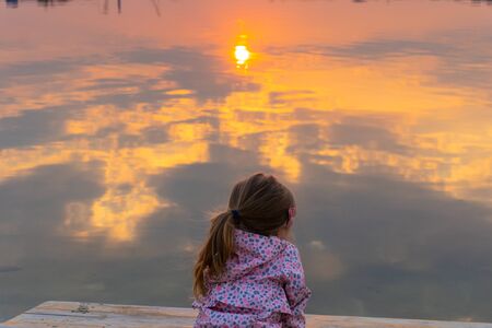 Sun reflection in water of lake or river and little girlの写真素材