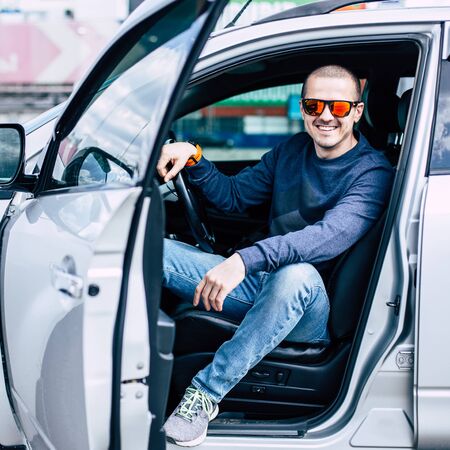 Man in sunglasses sitting in the car and smiling