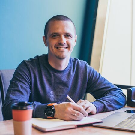 Man freelancer working in cafe and writing some notes in notebook