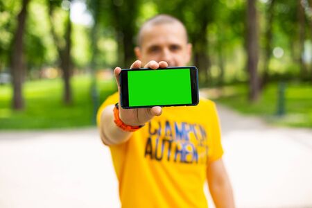 Man in yellow t-shirt holding smartphone in hands
