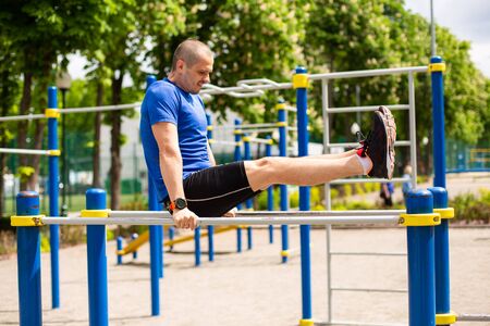 Man doing exercises on bars at sports groundの写真素材