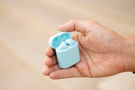 Man holding wireless earphones in charging boxの写真素材