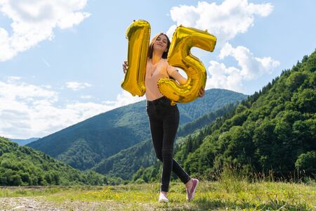 Happy teen girl with number 15th from balloons celebrating birthday