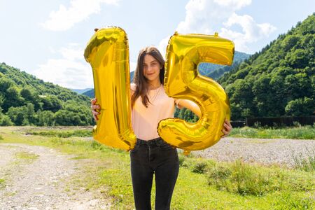 Teenage girl holding golden balloon with number 15thの写真素材