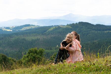 Woman and girl child having fun on hill with mountains behindの写真素材