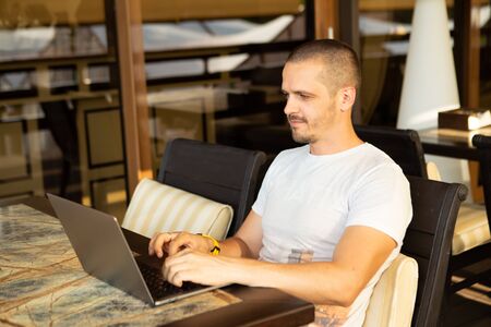 Man looking in laptop and working online sitting in cafeの写真素材