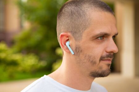 Man in wireless earphones listen music outdoor