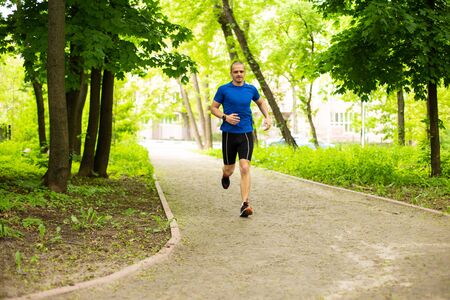 Man in blue tshirt run in the forest or parkの写真素材