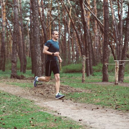 Athlete run in the pine summer forestの写真素材