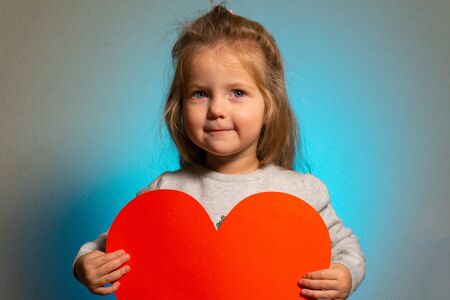 Little girl with red big blank heart looking in cameraの写真素材