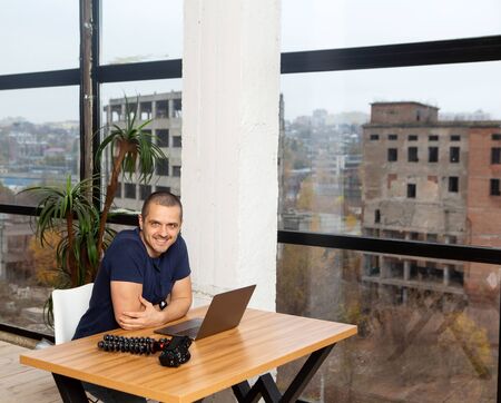 Man working from home and sitting at the table with laptop and camera