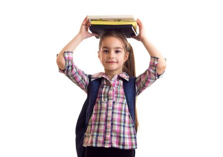 Cute schoolgirl holding books over her headの写真素材
