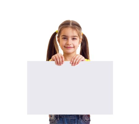 Little smiling girl looking in camera and holding white paper bannerの写真素材