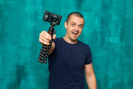 Happy man holding camera on tripod and looking in cameraの写真素材