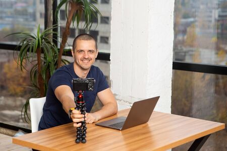 Smiling man blogger holding camera in tripodの写真素材