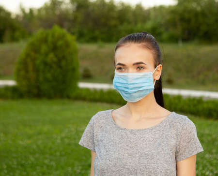 Portrait of woman in medical mask on her face outdoors.