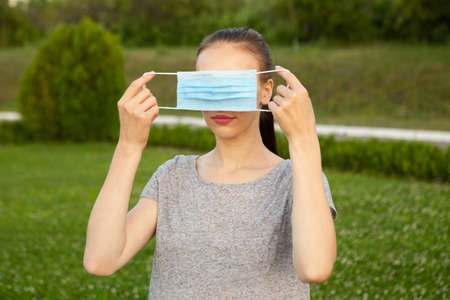 Woman holding face medical mask on her eyes.の写真素材