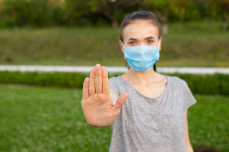 Woman in medical mask show stop gesture by handの写真素材