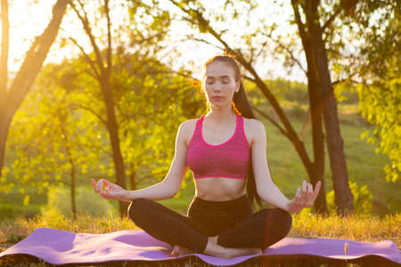 Girl is sitting in lotus position in the park.の写真素材