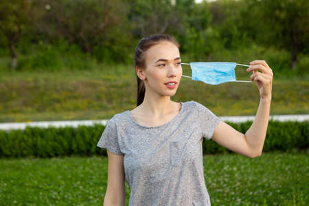 Young woman takes off medical mask and breath deeply and smiling looking aside.の写真素材