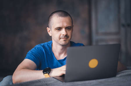 Adult man in blue t-shirt working on laptop