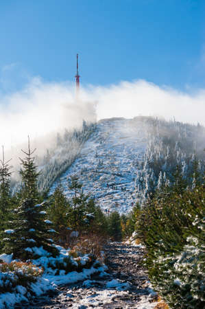 Panorama of hill Lysa hora in misty clouds during sunrise Beskydy Mountains. Transmitter on Lyse...