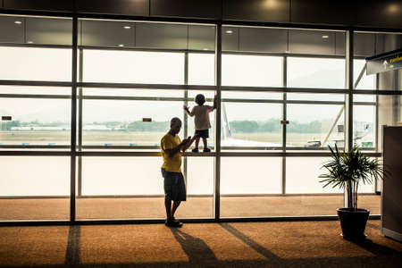 Chiang Mai, Thailand - 1 April, 2013: Father and son waiting for a flight to depart at the airportのeditorial素材