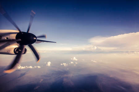 Flying to a tropical destination with an airplane wing and fluffy white clouds from high altitudeの写真素材