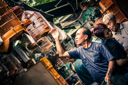 Hong Kong, China - May 21, 2009: Man feeding his birds at the Yuen Po Bird Garden in Mongkok districtのeditorial素材
