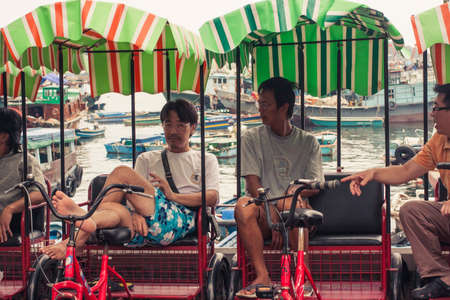 Hong Kong, China - 3  June, 2009: Rickshaw drivers relaxing during the daytime while waiting for customers at the ferry pier on Lamma Islandのeditorial素材