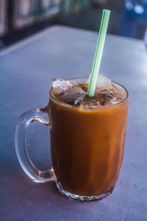 Malaysian coffee with milk and tea in a glass mugの写真素材