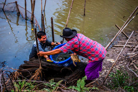 Nakhon Nayok, Thailand - 21 June, 2015: Local fishermen pulling a net out of a river at a sustainable fishing locationのeditorial素材